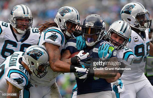 Luke Kuechly and Shaq Green-Thompson of the Carolina Panthers attempt to tackle Marshawn Lynch of the Seattle Seahawks during the NFC Divisional...