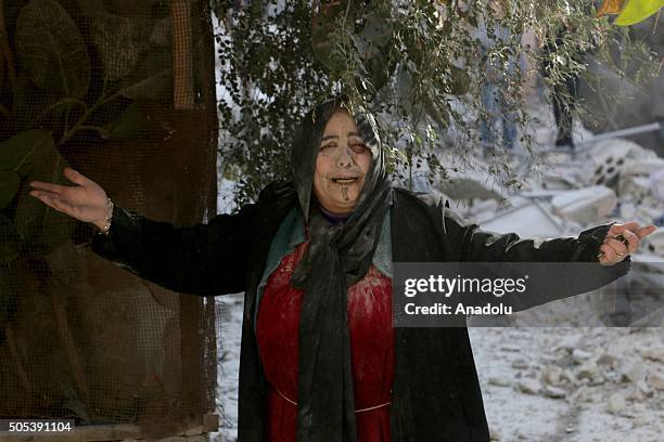 Woman cries out in front of a heavily damaged building after Russian airstrikes hit residential areas in Kallese District of Aleppo, Syria on January...