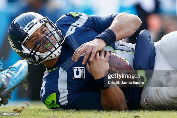 Russell Wilson of the Seattle Seahawks is knocked to the ground during the NFC Divisional Playoff Game against the Carolina Panthers at Bank of...