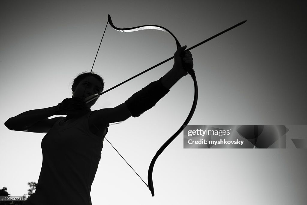 Female archer in the field at sunset