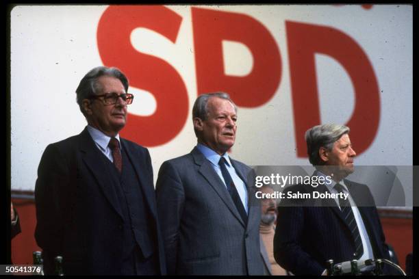 Former West German Chancellors Helmut Schmidt and Willy Brandt standing with Chancellor candidate Hans Jochen Vogel at Social Democratic Party...