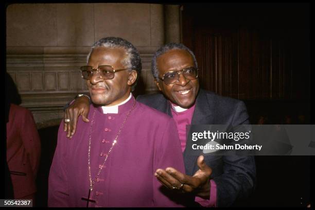 Archbishop Desmond Tutu standing with arm around life-like wax dummy of himself at Madame Tussaud's wax museum.