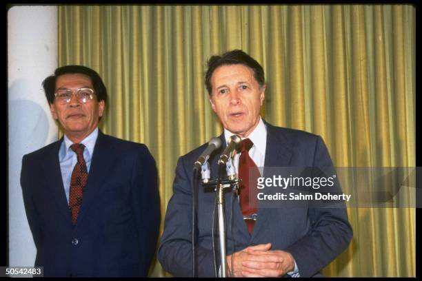 Secretary of Defense Caspar Weinberger speaking into microphone as Philippine Defense Minister Juan Ponce Enrile stands next to him.