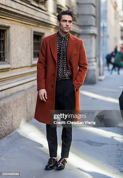 Spanish supermodel Jon Kortajarena wearing a dark orange peacoat, printed tie and shirt, and dark pleated trousers outside Salvatore Ferragamo during...