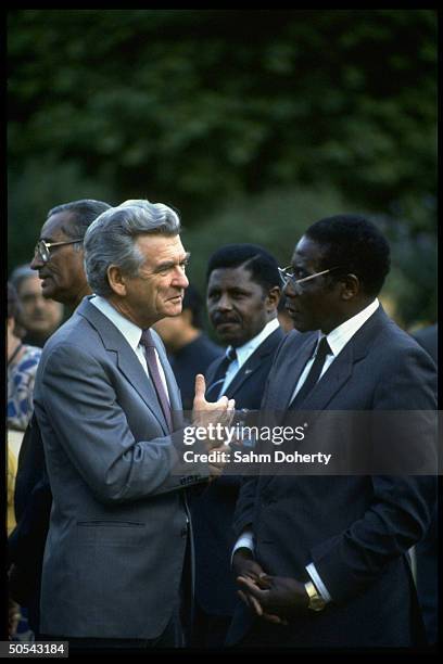 Australian PM Robert Hawke chatting w. Zimbabwe ldr. Robert Mugabe outside Commonwealth meeting