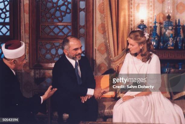 Jordan's King Hussein sitting with bride Lisa Halaby during their wedding ceremony at the royal palace.