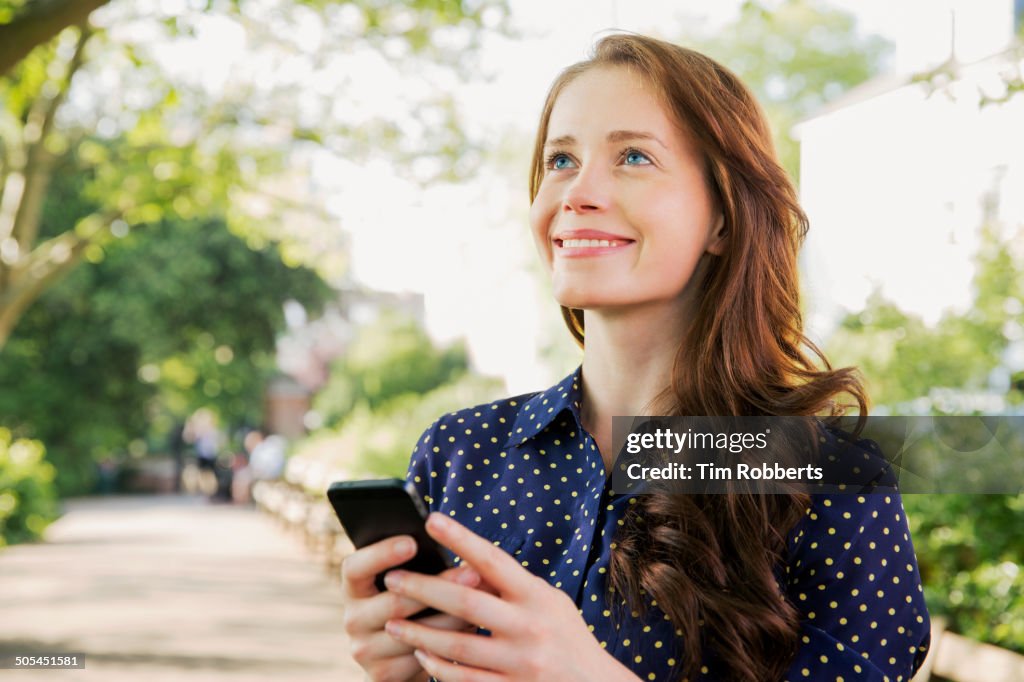 Woman using smart phone outside.