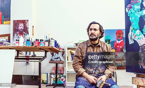 mann sitzt auf der vorderseite von tafel im art sudio - künstler stock-fotos und bilder