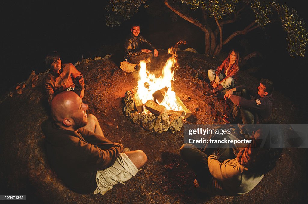 Lagerfeuer-Freunde in circle auf dem Feuer