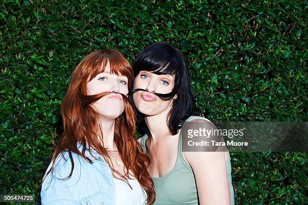 two women making moustaches with hair - friend mischief stock-fotos und bilder