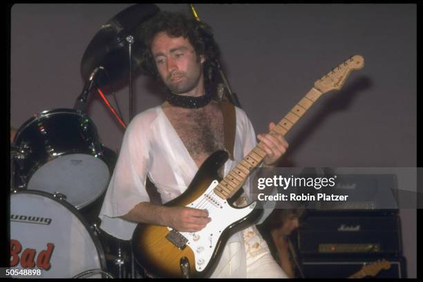 Singer Paul Rodgers of rock band Bad Company playing guitar in concert.