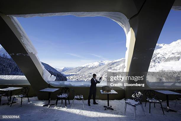 Hotel employee checks a bottle of champagne as he stands on the snow covered bar terrace of the InterContinental Hotel Davos, operated by...