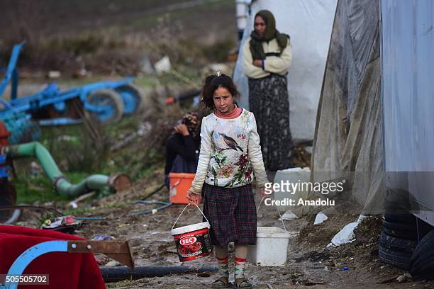 Syrian refugee girl carries buckets near a makeshift tent in the Serik district of Antalya, Turkey on January 18, 2016. Because of the high wind and...