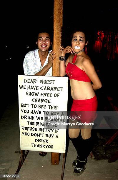 Young man and a performer standing next to a sign detailing the house rules, outside a Kathoey or ladyboy cabaret show in Thailand, 2006.