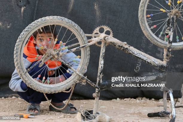 Boy fixes his bike at Zaatari refugee camp, close to the northern Jordanian city of Mafraq on January 18, 2016.