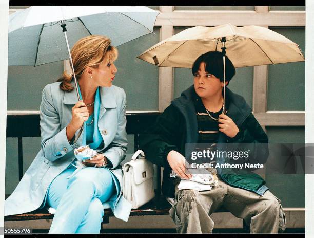 Actors Edie Falco, left, and Robert Iler holding umbrellas during a scene from TV series 'The Sopranos', circa 1999.