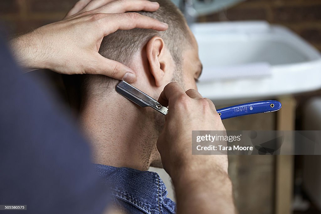 Man getting hair cut with razor