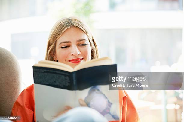 woman smiling and reading book - lezen stockfoto's en -beelden