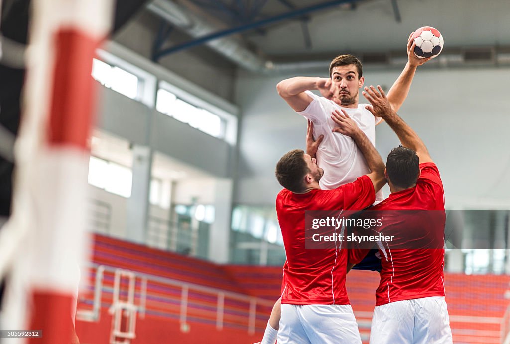 Handball player jumping and shooting at goal.