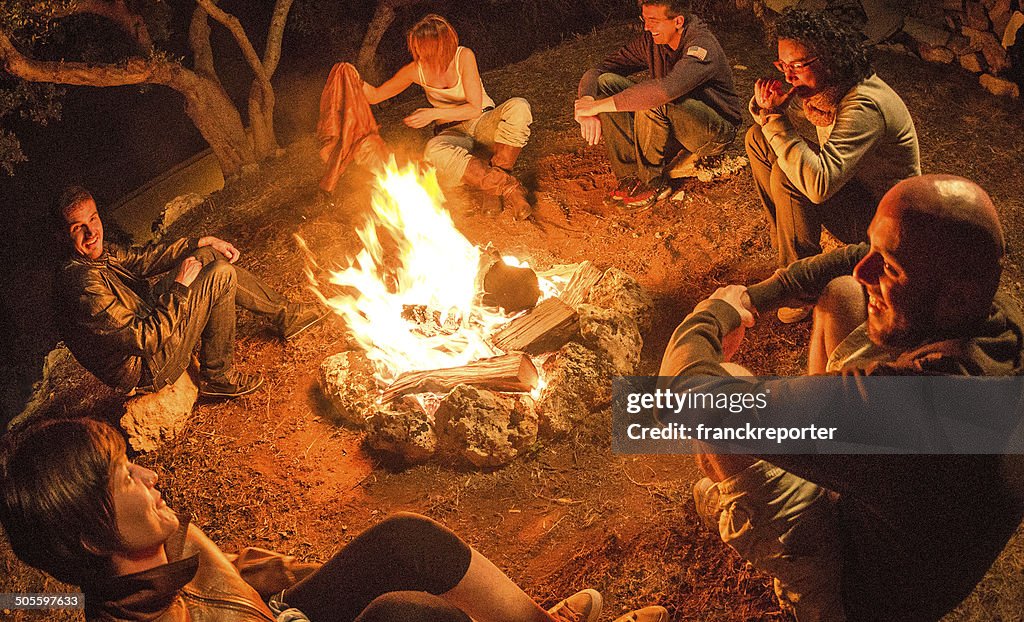 Lagerfeuer-Freunde in circle auf dem Feuer