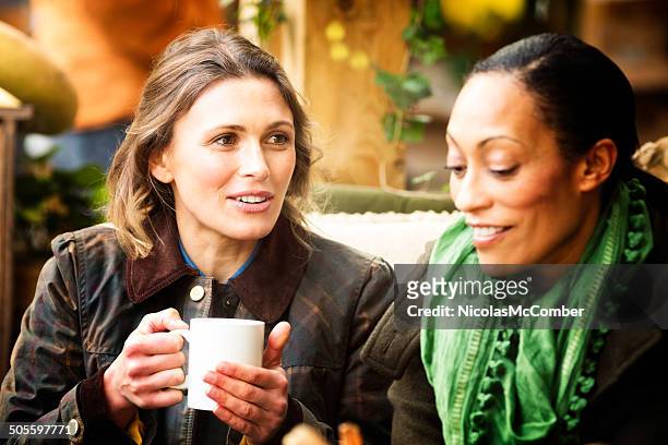 two female friends having coffee at cafe - women friends stock pictures, royalty-free photos & images