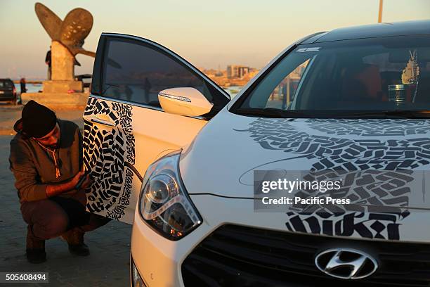 Palestinian artist Belal Khaled intricately paints graffiti on the car.
