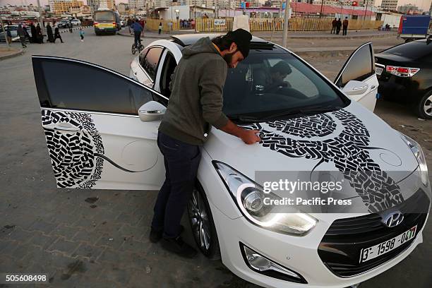 Palestinian artist Belal Khaled intricately paints graffiti on the car.