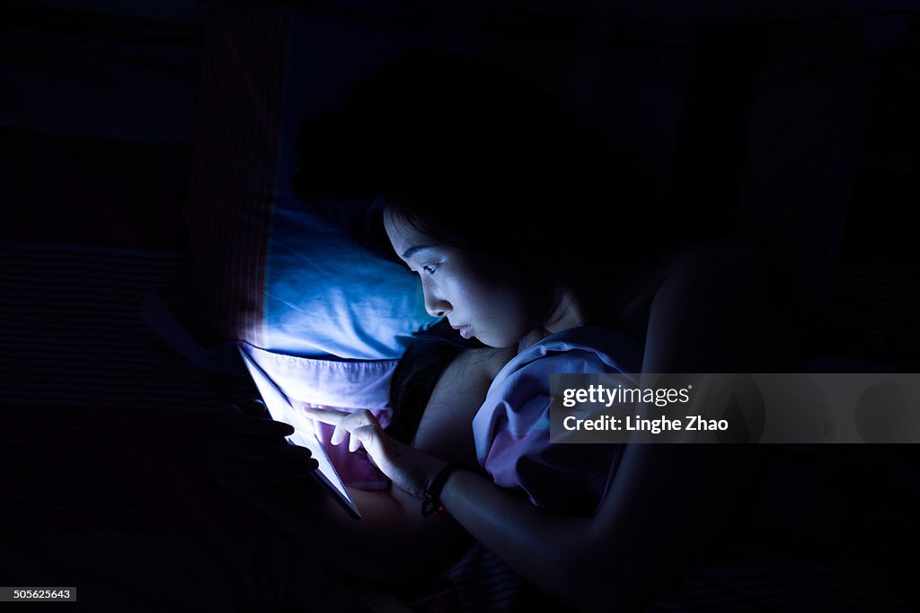 Asian women see tablet computer in bed