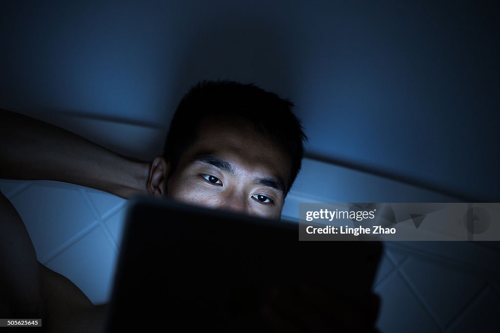 Asian men see tablet computer in bed