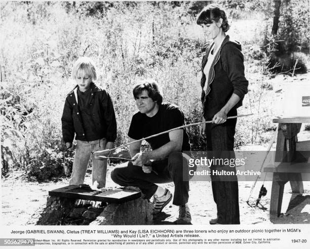 Gabriel Swann, Treat Williams and Lisa Eichhorn roast hot dogs in a scene from the MGM movie "Why Would I Lie?" circa 1980.