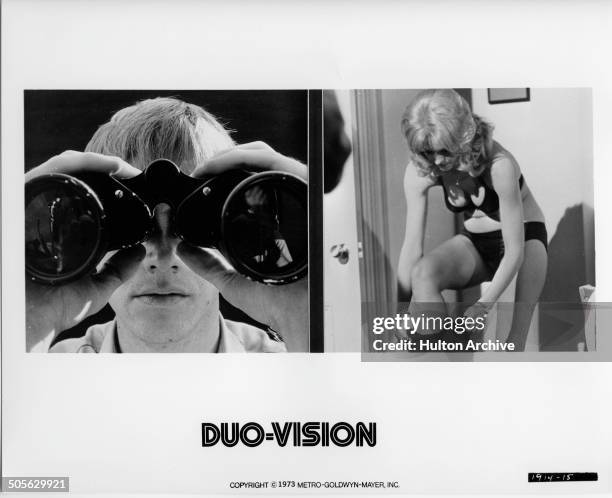 Randolph Roberts peers through binoculars, Diane McBain dresses in a scene from the MGM movie "Wicked, Wicked" circa 1973.