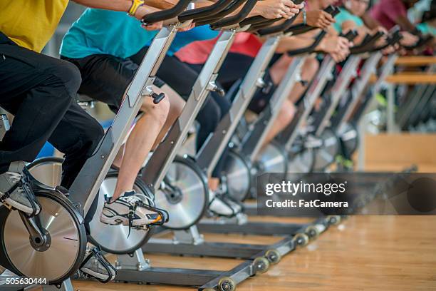 cycling in a fitness class - stationary cycling class stock pictures, royalty-free photos & images