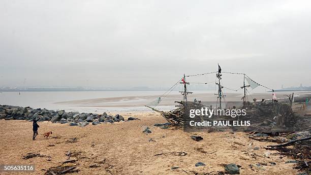 Man walks his dog by the Black Pearl driftwood pirate ship on the beach of the River Mersey at New Brighton in north west England on January 19,...