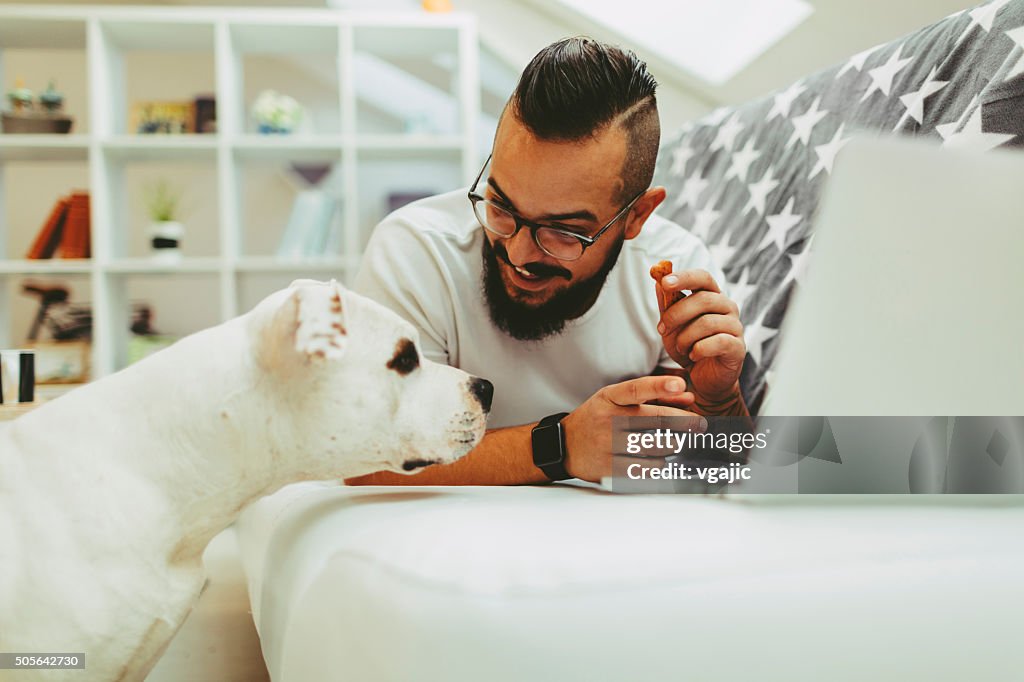 Man giving biscuit to his dog