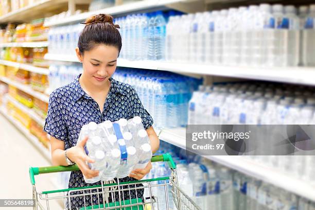 asian woman buys in the supermarket bottle of water - water bottles stock pictures, royalty-free photos & images
