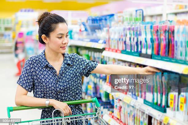 asiatische frau kauft einer zahnbürste - zahnpasta stock-fotos und bilder