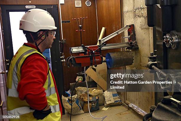 Diamond driller Sunny Kirby looks on as a drill is positioned to drill another hole in the wall used by burglars to access the underground vault of...