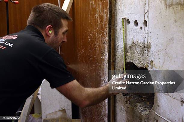 Diamond driller Jason Grace measures a hole as he re-drills the hole in the wall used by burglars to access the underground vault of the Hatton...