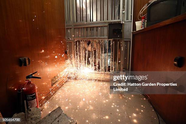 Caretaker cuts through the bars of a reinforced door that was broken through to access the underground vault of the Hatton Garden Safe Deposit...