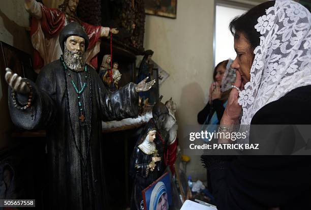 Lebanese Christian women pray in front of statues depicting Christian holy figures during a mystical quasi-religious service in an appartment in a...