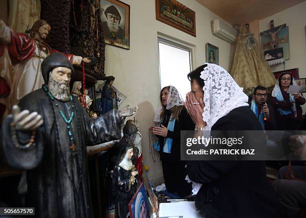 Lebanese Christian women pray in front of statues depicting Christian holy figures during a mystical quasi-religious service in an appartment in a...