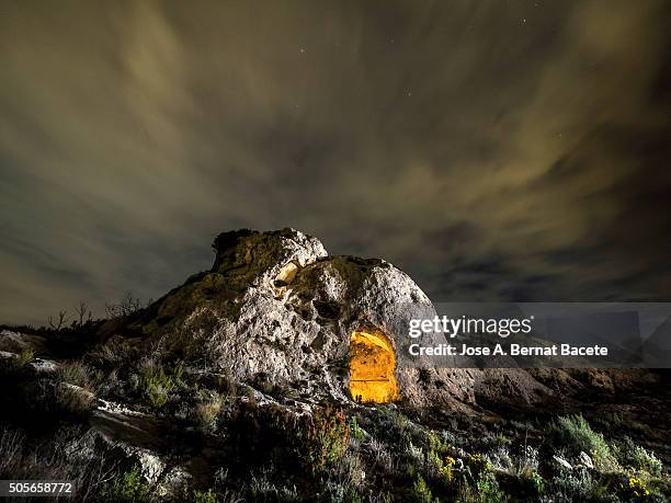 rock on the top of a mountain with a refuge excavated in his interior during the night - luz al final del túnel fotografías e imágenes de stock