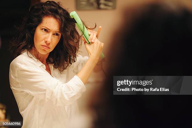 woman using hair straightener - haar straighten stockfoto's en -beelden