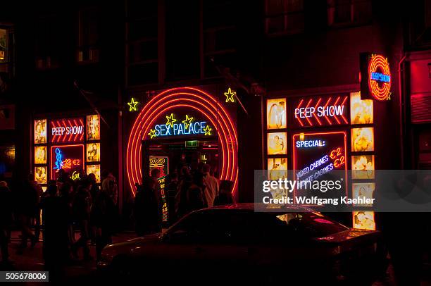 Street scene at night with colorful neon signs of a sex shop in the red light district of Amsterdam in the Netherlands .