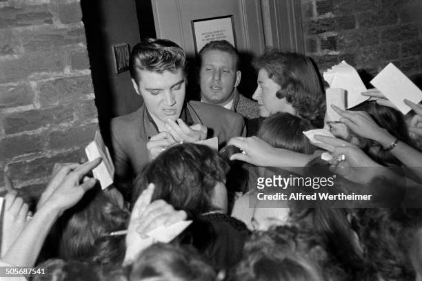 Alfred Wertheimer/MUUS Collection via Getty Images) American musician Elvis Presley signs autographs for fans at the CBS-TV Studio 50 stage door, New...