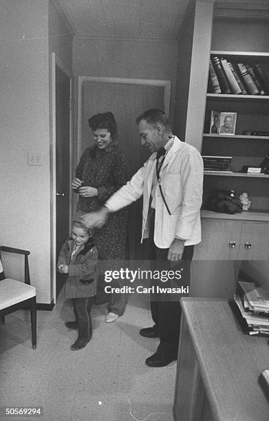 Dr.Ernest Ceriani patting a patient's head.