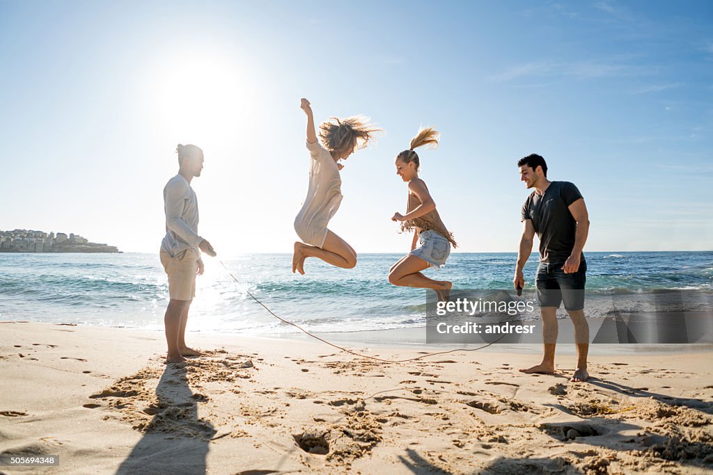 Freunde springen Seil am Strand