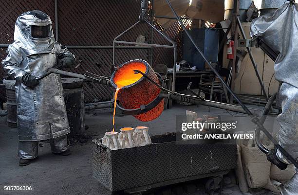 Workers in fire suits pour molten bronze metal into molds during the casting of the Screen Actors Guild Award statuettes, at the American Fine Arts...
