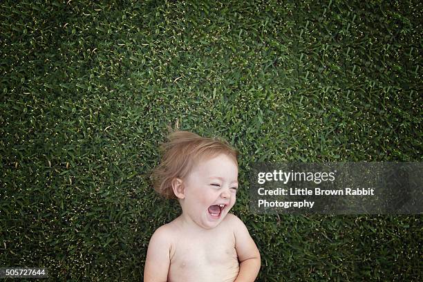 laughing baby lying on green grass - baby laughing stock pictures, royalty-free photos & images