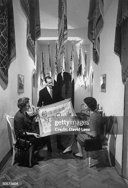 Fashion designer Emilio Pucci showing new scarf to clients in showroom of his salon.